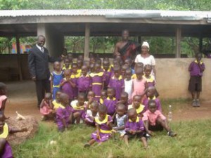Alex Obruni, Onsite Project Manager (in suit) and Thaddeus Mensah, SCEP Co-founder with school children and teacher.